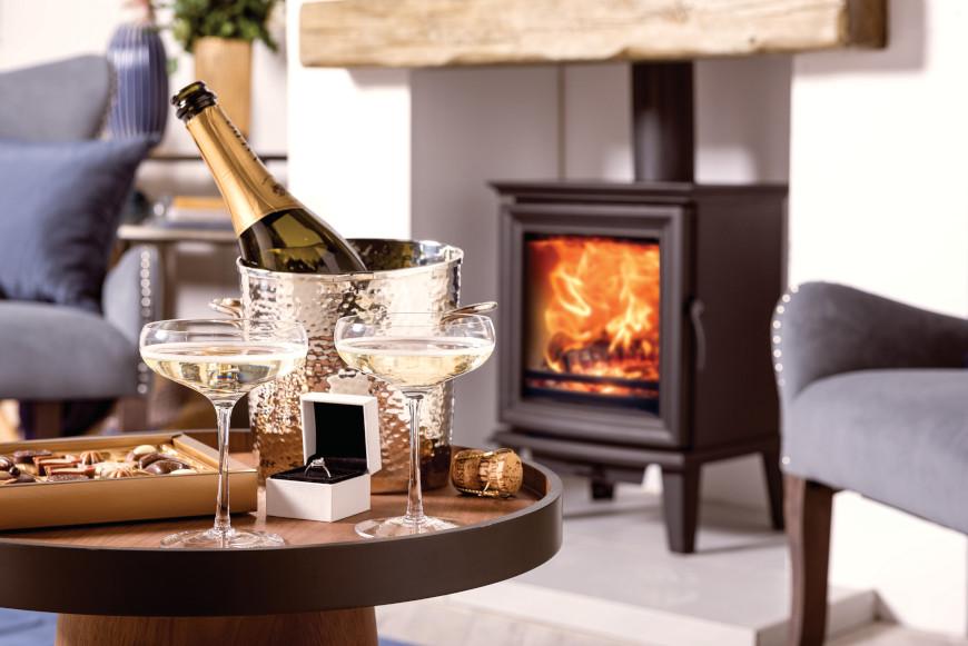 Romantic chocolates and champagne by a log burner for a proposal