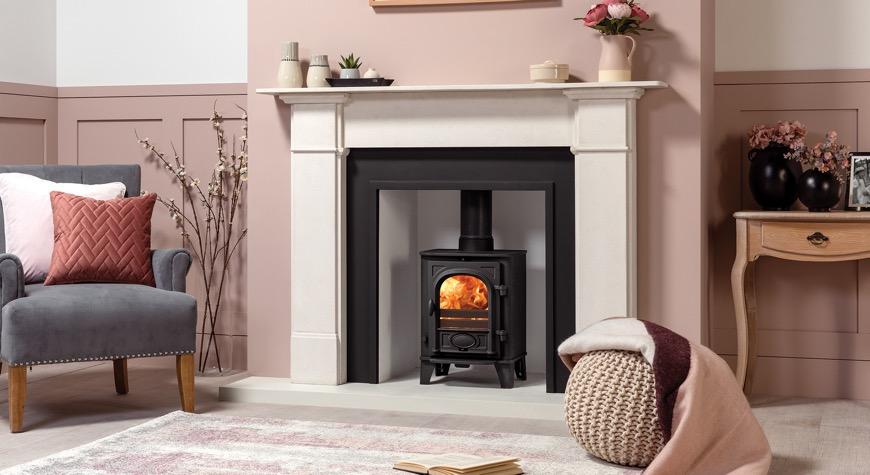 Stockton 3 Multi-fuel Ecodesign stove burning logs, Shown with Chelsea London Cast Front in Matt Black and Claremont Limestone Mantel