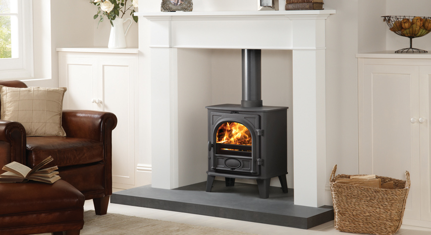 Multi-fuel version of the Stovax Stockton 5 stove with external riddling. Shown  here in Matt Black, burning logs with Brompton mantel in White also available from Stovax.